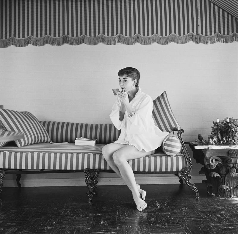 Mark Shaw Mark Shaw AUDREY HEPBURN ON STRIPED SOFA APPLIES LIPSTICK 1954