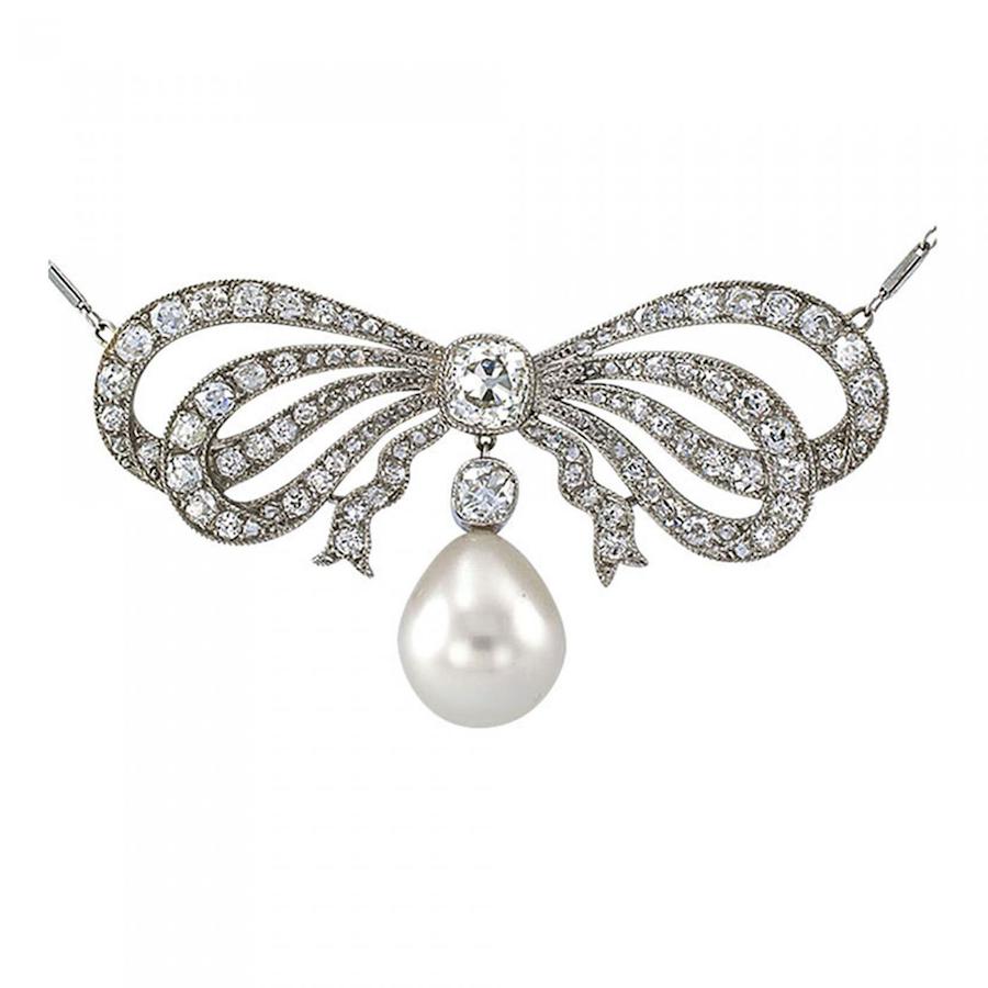 Antique Edwardian diamond and pearl bow necklace circa 1910. Centering upon a nice old Mine Cushion cut diamond weighing approximately 1.00 carat, approximately I - J color and VS clarity, tied up with a voluminous platinum bow, set with approximately 3.10 carats of smaller similarly-cut diamonds, approximately H - I color and VS clarity, plus a teardrop-shaped cultured pearl measuring approximately 11 x 13 mm, completed by a 16
