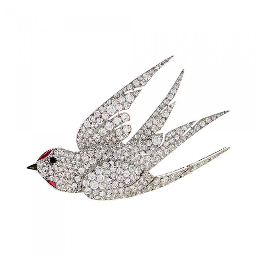 A French Art Deco platinum and enamel brooch with diamonds and rubies, c. late 1930s. The brooch has 306 round diamonds with an approximate total weight of 8.75 carats, and 2 cabochon ruby accents. This dimensional brooch representing a dove, the symbol of peace and love, is of special significance, as it was produced as France and the European continent were heading towards war. Offered by Macklowe Gallery.