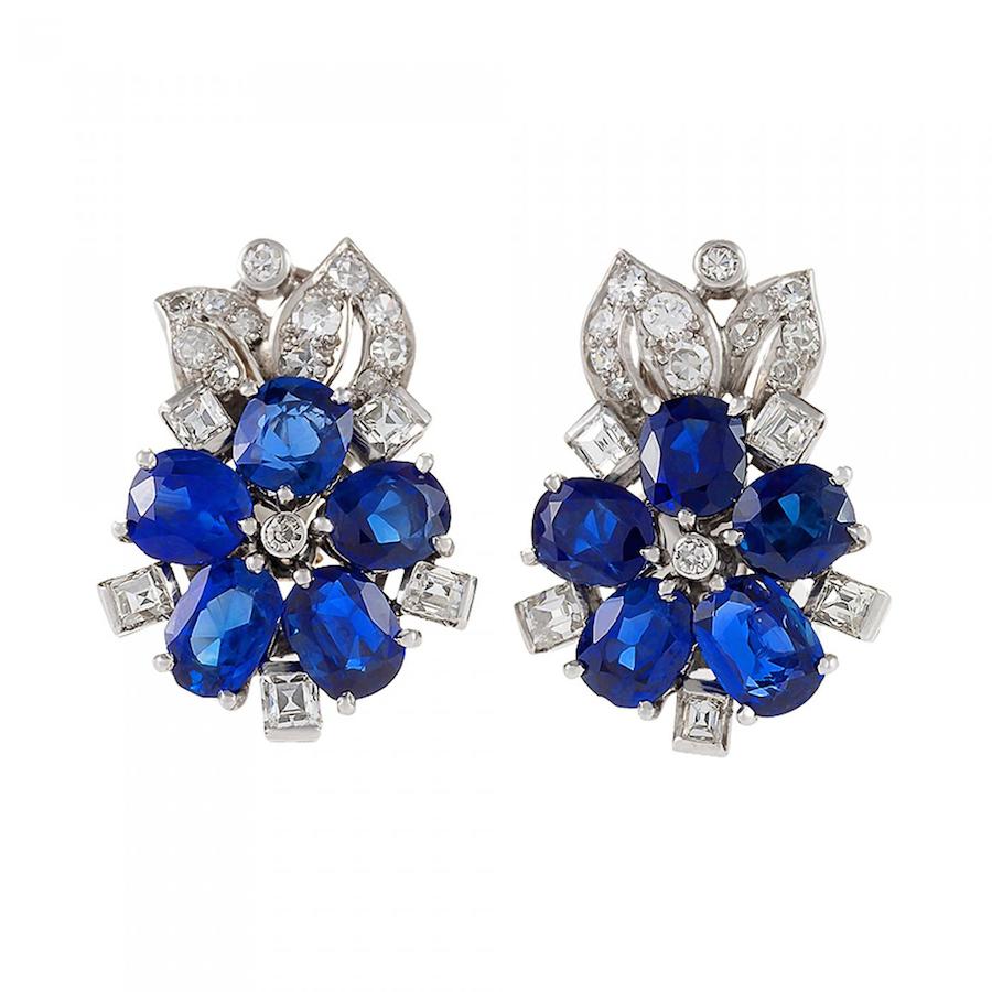 A pair of Retro platinum earrings with sapphires and diamonds, c. 1930s. The earrings have 10 oval-cut sapphires with an approximate total weight of 3.20 carats, with 36 square-cut & round-cut diamonds with an approximate total weight of 1.00 carats. The earrings are in a floral motif with diamond leaf details. Offered by Macklowe Gallery.