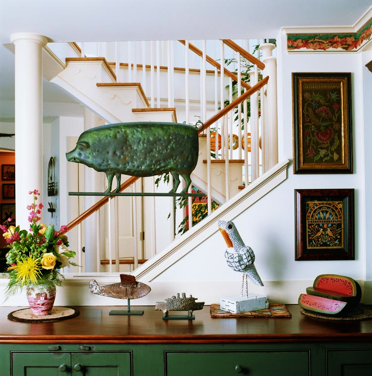 Central to this kitchen alcove is the large pig vane from the David Davies collection. It was also owned by curator, dealer, and scholar Robert Bishop and is illustrated on page 62 of his American Weathervanes and Whirligigs (1981). Beneath this piece are two Coney Island iron shooting-gallery targets, a carved owl by outsider artist John Gilly, and a contemporary carved wood and painted watermelon and slice. Mounted on the wall is a silk thread on linen crewel work wrought by Alice Woodwell for her father Gideon Woodwell and dated 1766. (Another crewel work by the same young girl is illustrated on page 88 in Bolton and Coe, American Samplers (1921).) On the wall below it is a watercolor cutwork picture on brown silk backing from 1820 to 1830, from the collections of Betty Sterling, the Garbisch Collection, Barry Cohen, and Dr. and Mrs. Ed Hoffman.
