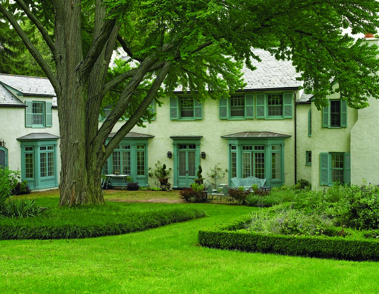 The rear of the collectors’ home, showing the new addition at left, reads like a French provincial house, with stucco walls, finely detailed bay windows, and trim in a particular shade of blue, which is based on a historic color palette.