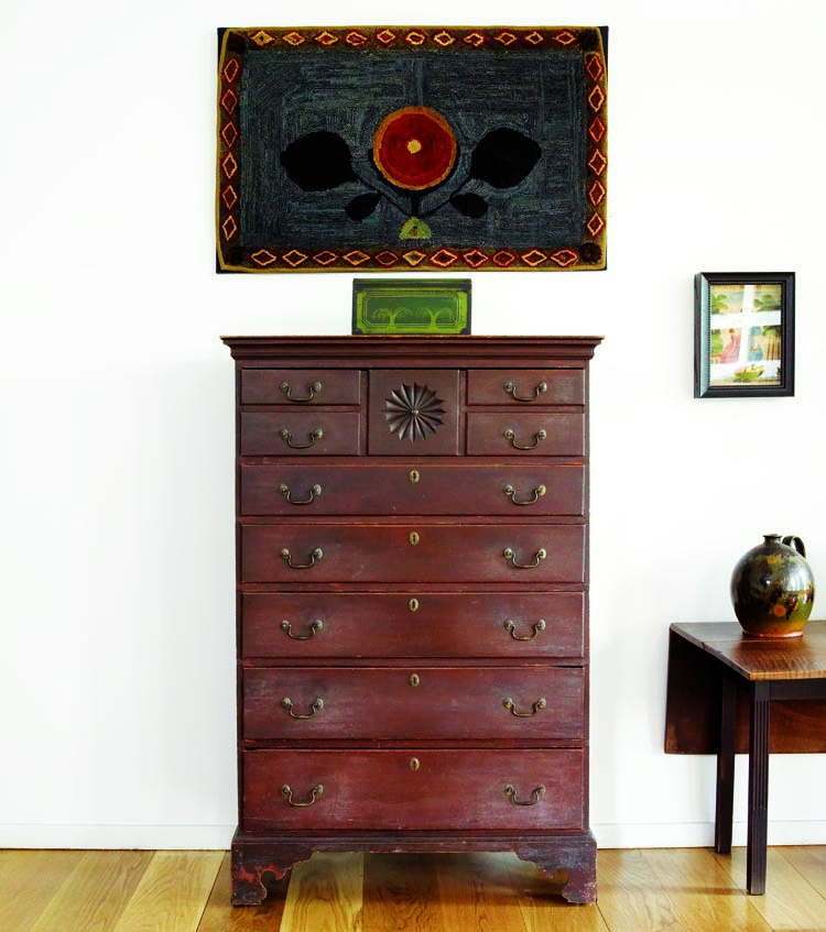 The top drawer on this Sanbornton, New Hampshire, tall-chest of circa 1790–1810 is fashioned to resemble four drawers flanking a center drawer, a design feature also seen on a high chest illustrated in Furniture of Historic Deerfield by Dean Fales (New York, 1976; illus. 400). Probably from Vermont, the circa-1825 dome-top box is painted in a delicate pattern of yellow sprigs on a red and green ground. The New England hooked rug dates to circa 1850–60.