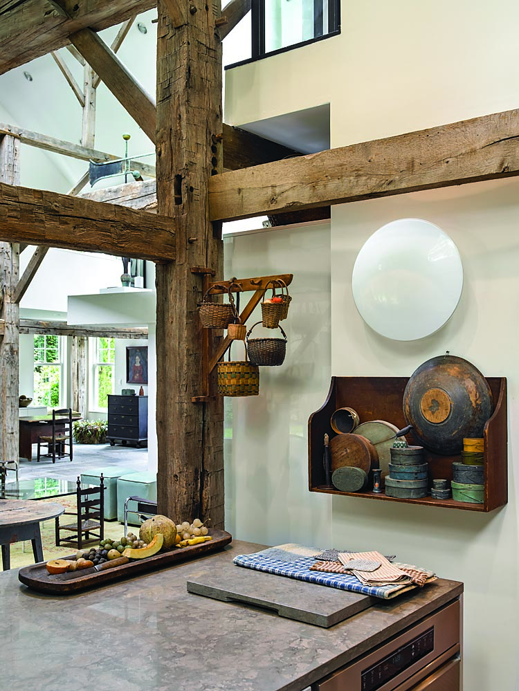 Looking out from the kitchen to the main living space, examples of the owner’s favorite miniatures are displayed—hanging berry baskets and Shaker boxes. Color is always a part of the decorative scheme, picked up even in the early textiles on the counter. The long wooden tray is filled with “everlasting” stone and wax fruit. The owner is always refining for shape, color, and objects that speak to her soul.