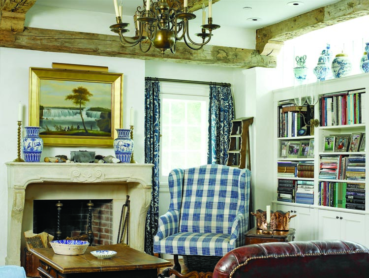 The sitting area in the home’s new addition derives its European character from a French mantel and hand-hewn wooden beams. The blue and white color scheme is carried into this room through the upholstery on an early-nineteenth-century French wing chair, boldly patterned drapes, and with Delft pieces displayed atop the bookcase. The Edmund C. Coates (1816–1871) painting of Niagara Falls, done in 1850, at the time when the Falls was considered the nation’s most stunning natural wonder, was one of the first pieces the couple bought (from Godel & Co.) after purchasing the house.