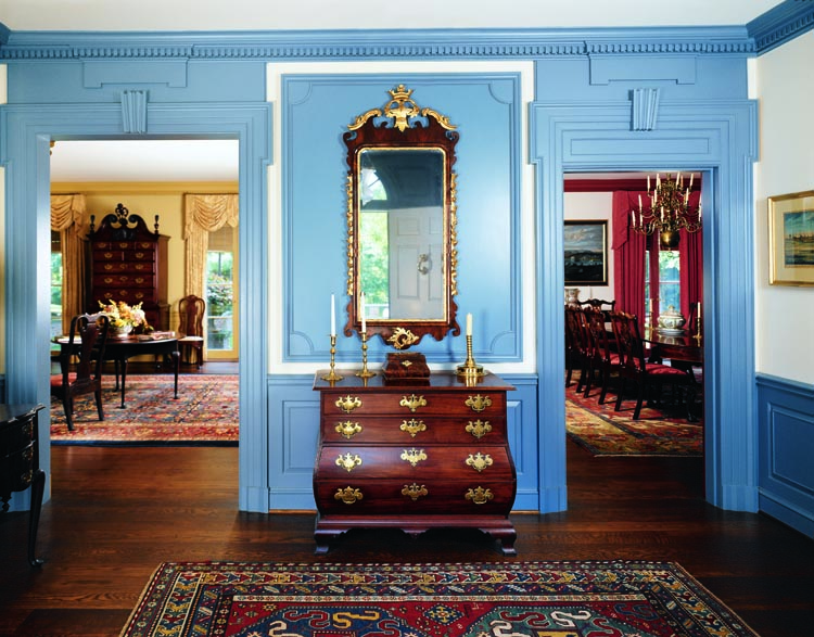 Set in the pier between the two rooms beyond is one of two Boston bombé chests of drawers in the collection. This chest was the first of the two purchased and was located by Jess Pavey when the couple lived in Michigan. It descended in the Crowninshield family of Salem, Mass. In the mid-eighteenth century, the form was among the most extravagant because of the skill necessary for its production and for the amount of expensive imported mahogany that was planed away in forming the kettle-shaped sides. A small box set on top shares the swelled sides of the chest. Although purchased prior to their move to this house, the eighteenth-century looking glass perfectly fits the space. It descended in the family of General Nathaniel Greene of Rhode Island, one of three generals to serve the entire length of the Revolutionary War, the others being Washington and Henry Knox.
